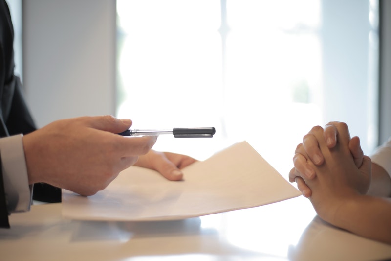 Image of man handing pen to someone to sign a document.